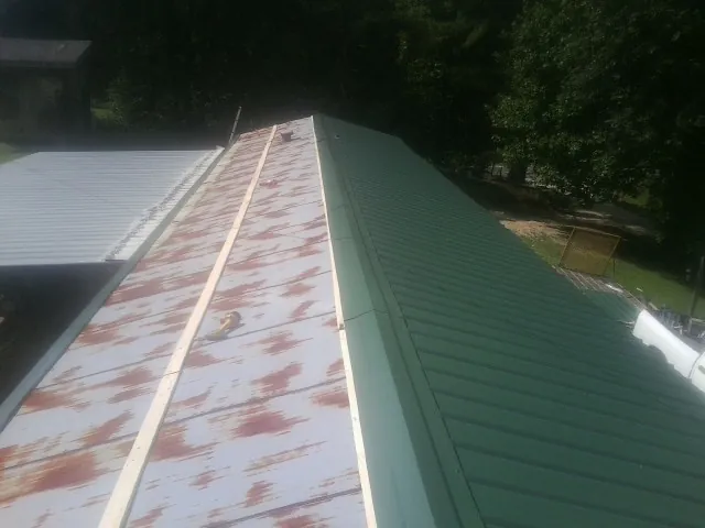 Old rusted panels beside newly installed green metal roofing — Wind Damage Roof Repair by Roofing Brothers in Chapel Hill