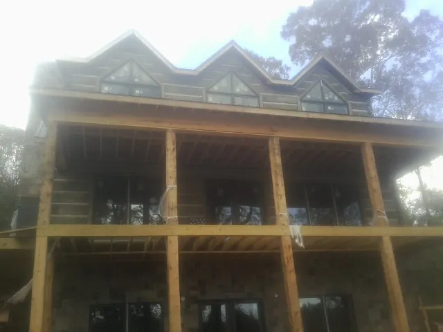 Dormers and porch framing on a large log home under construction — Roof Coating work by our crew in Chapel Hill