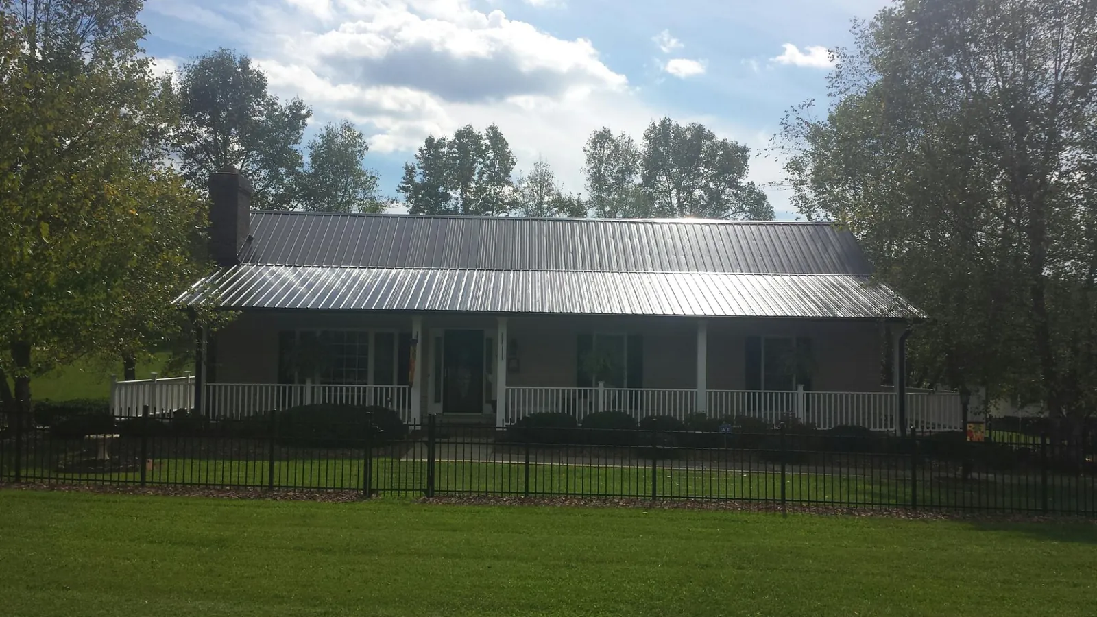 Gray metal roof on a brick ranch with a full width front porch — Gutter Guard Installation work by our crew in Chapel Hill